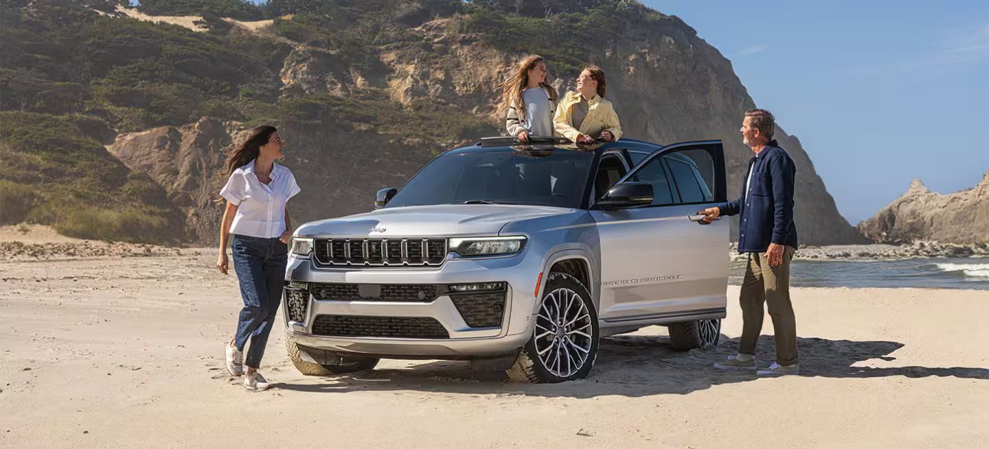 2026 Jeep Grand Cherokee parked on the beach with people by the vehicle