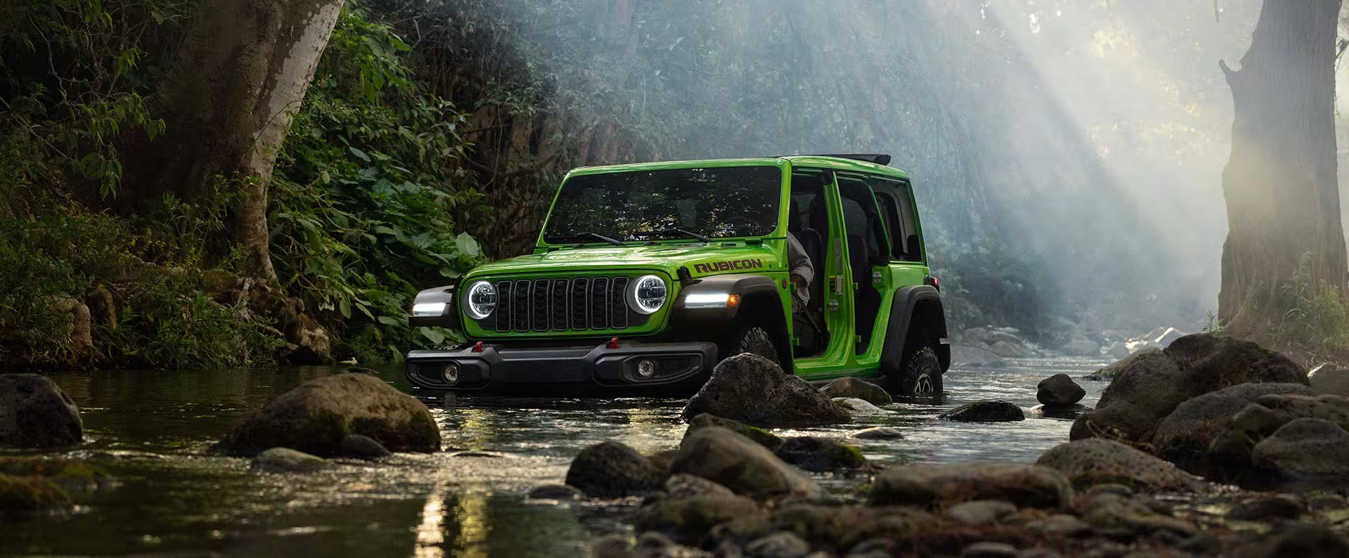 a new 2026 jeep wrangler parked in a creek in the forest