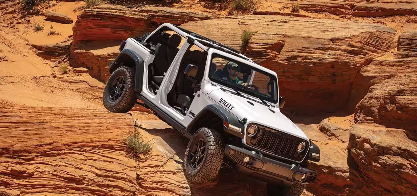 2026 Jeep Wrangler driving down a rock