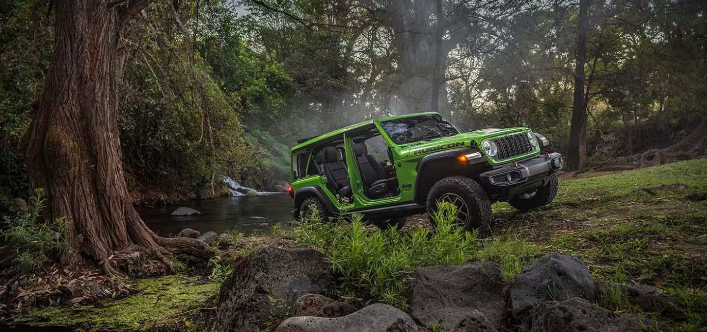 a new 2026 jeep wrangler parked in a creek in the forest