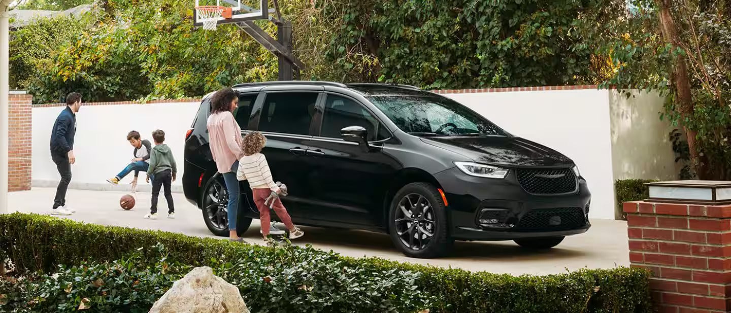 2026 Chrysler Pacifica parked at a house with a family walking towards vehicle