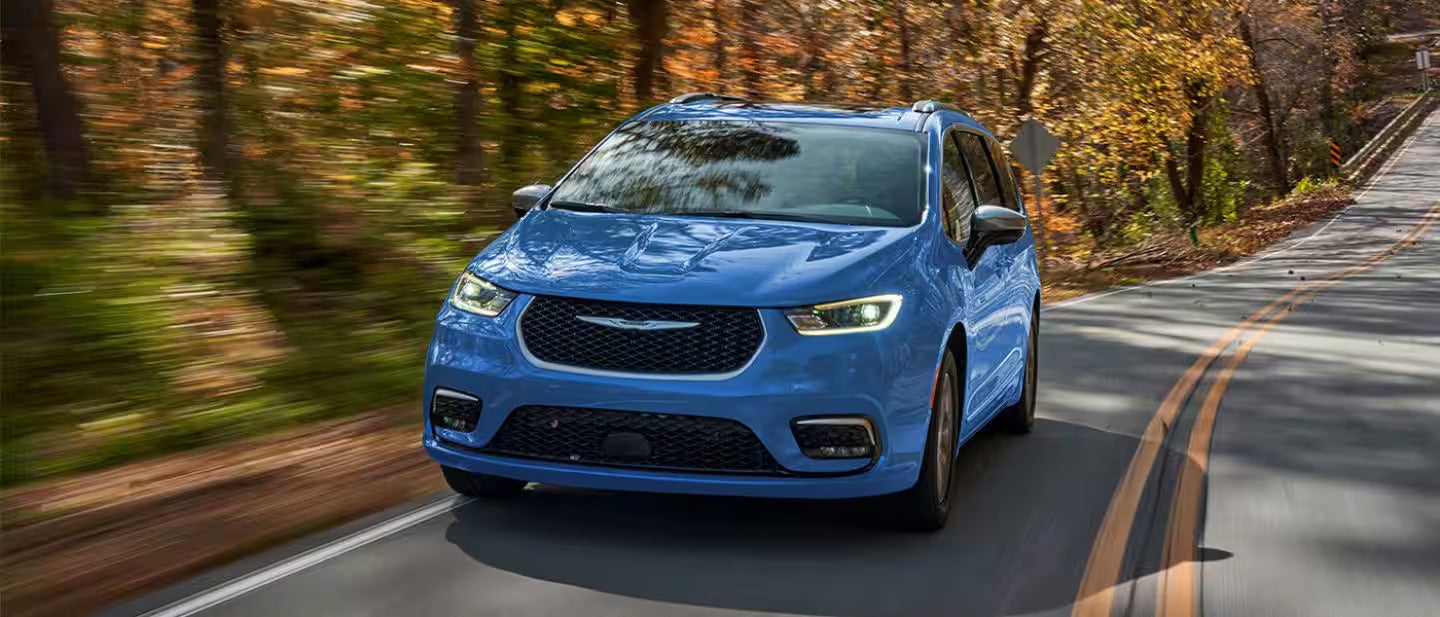 2026 Pacifica Plug-in Hybrid driving on a road with trees in the back ground