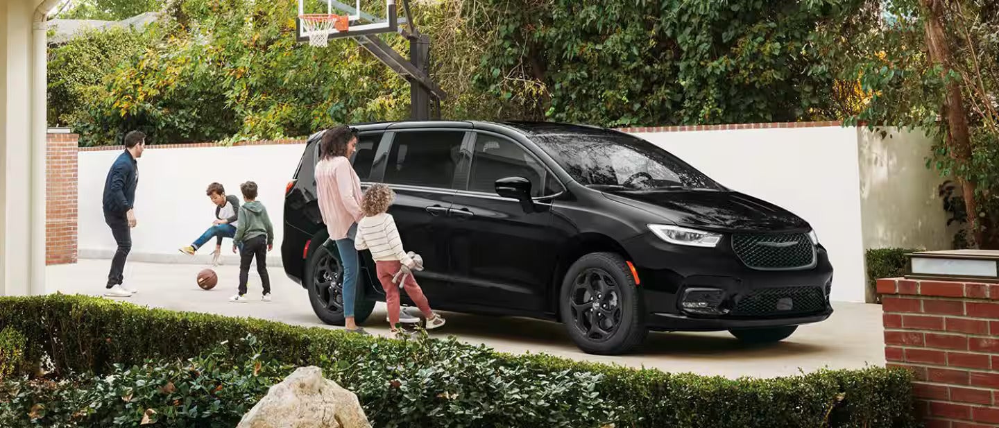 2026 Pacifica Plug-in Hybrid parked in front of a house with a family around the vehicle