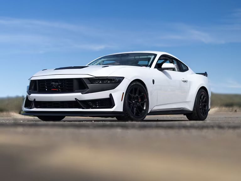 a ford mustang dark horse r in white parked on a paved road