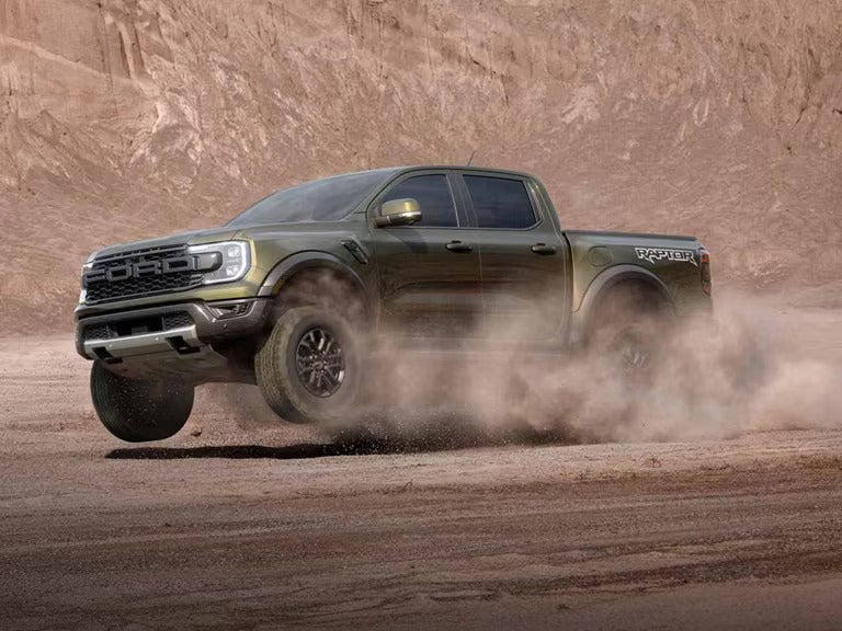 a dark ford ranger raptor driving in sand