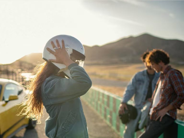 a group of people standing next to a racetrack with helmets