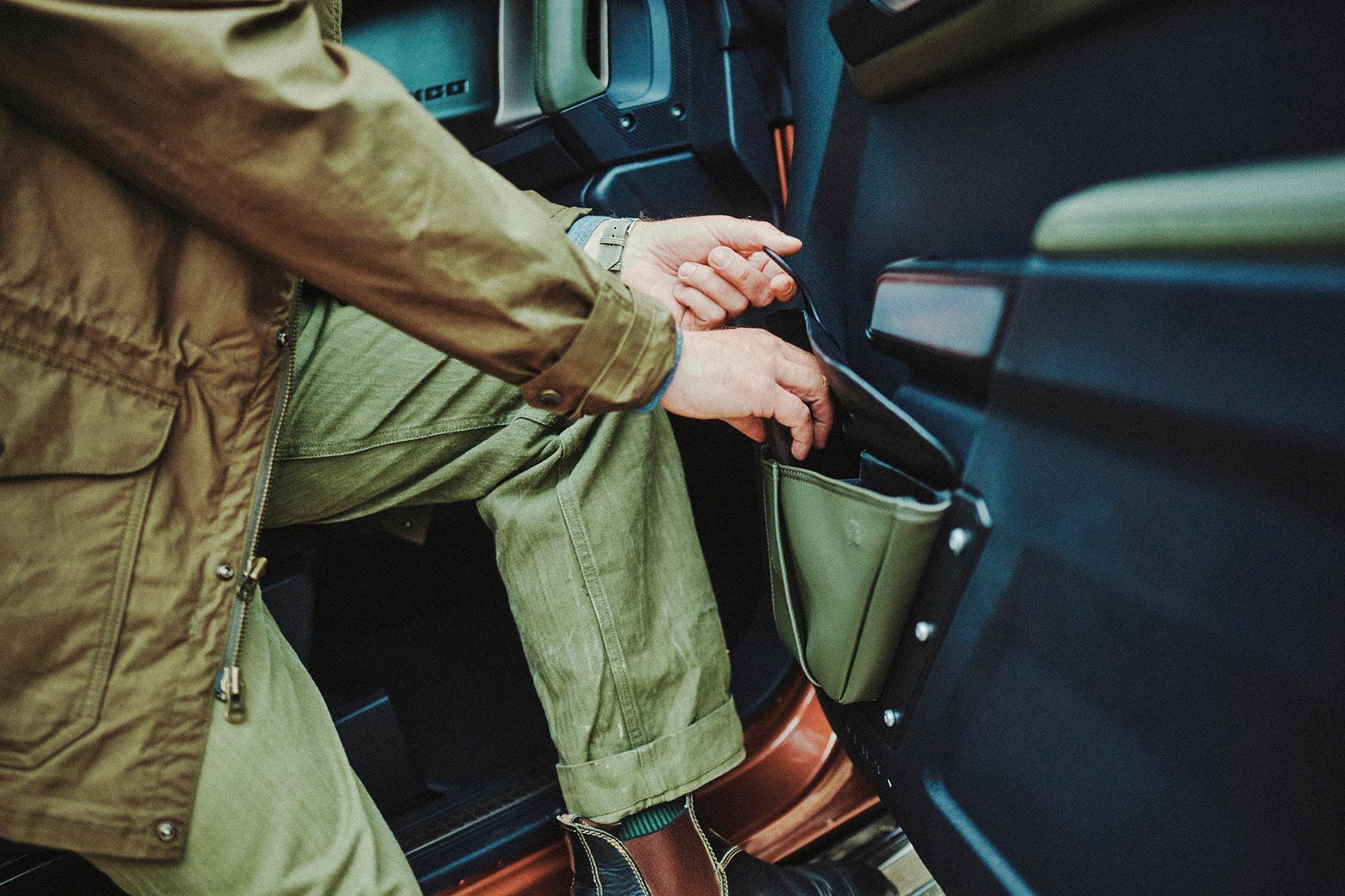 Driver reaching into the green canvas storage pocket inside a 2026 Ford Bronco