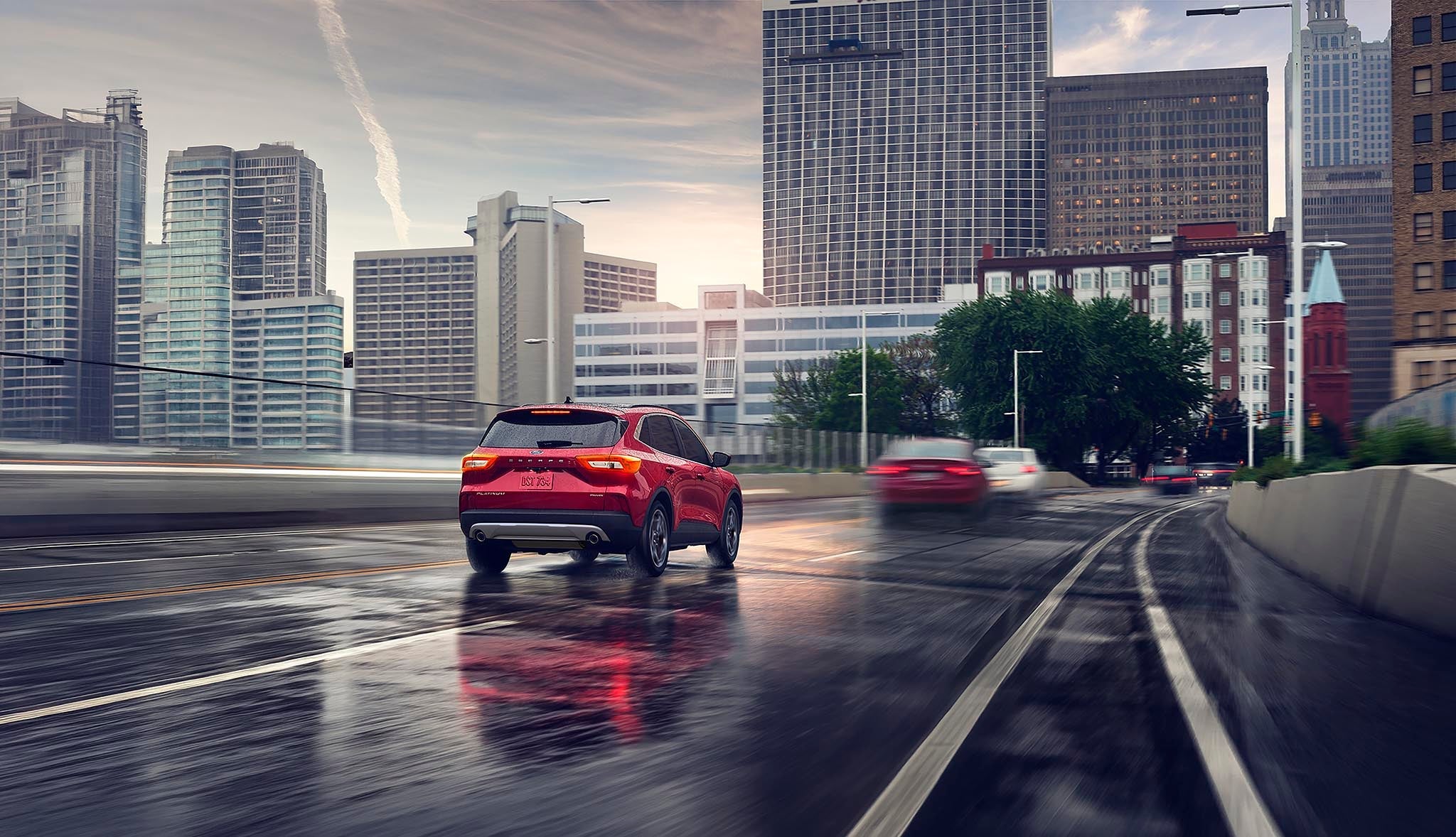 2026 Ford Escape driving down a city street with buildings in the background