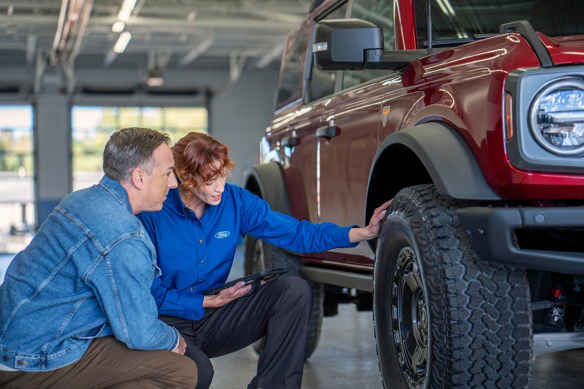 Ford service representative and vehicle owner checking tire wear on a Bronco