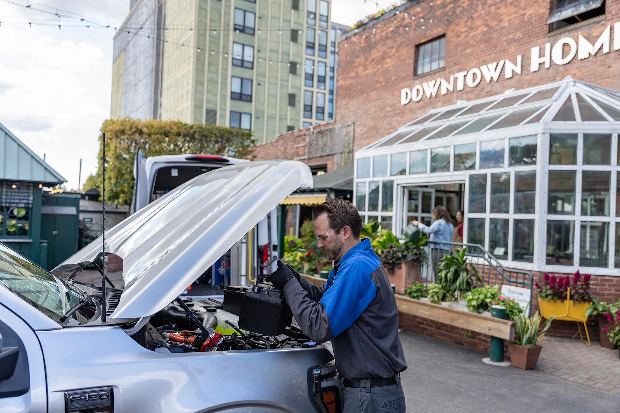 Ford Mobile Service technician replacing a vehicle battery under an open hood