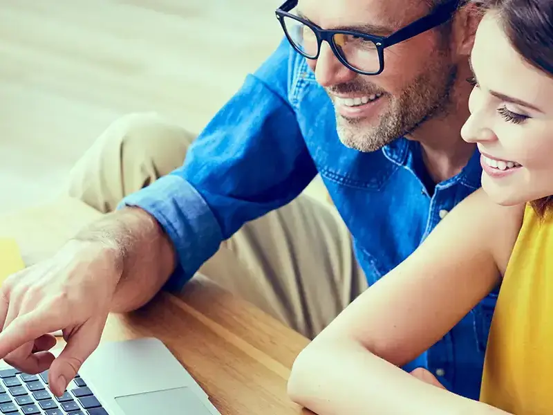 a man and woman looking at a laptop